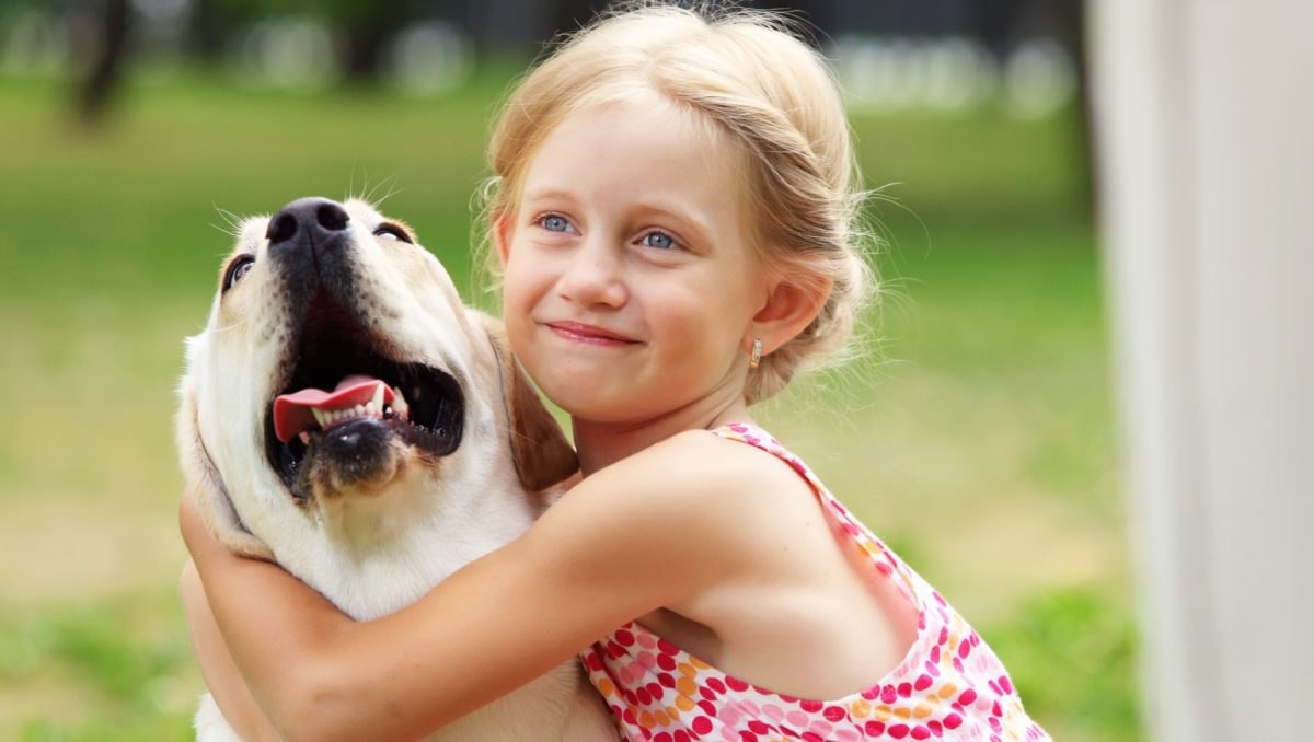 Girl her dog. Счастливые объятия девочки с щенком. Собака облизывает маленькую девочку. Счастливая девочка обнимает собаку. Фото счастливая девочка и собака.